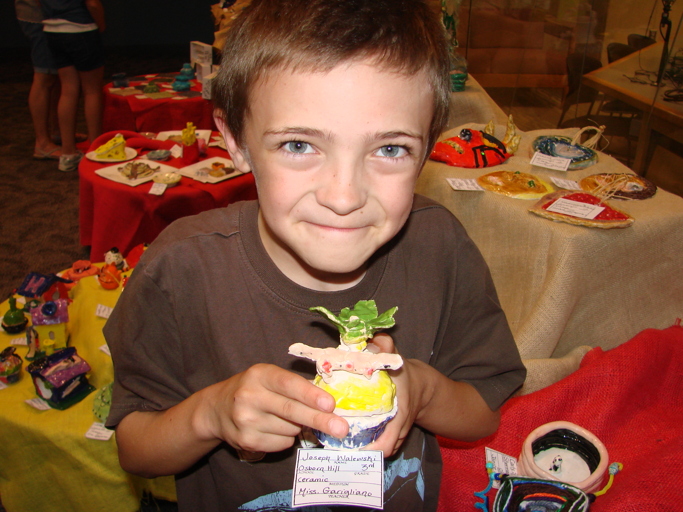 A picture of me from June 2010 holding a ceramic cupcake with a newt on top that I designed for art class